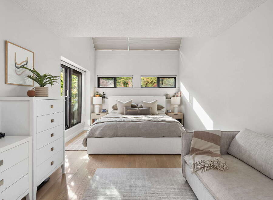 Experience modern comfort in this serene bedroom, featuring a plush king-sized bed adorned with neutral-toned linens and decorative pillows.
