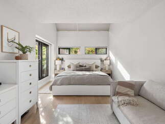 Experience modern comfort in this serene bedroom, featuring a plush king-sized bed adorned with neutral-toned linens and decorative pillows.