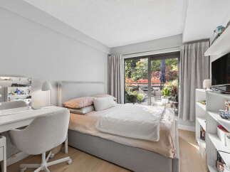 This cozy bedroom features a comfortable bed with plush bedding, a stylish vanity with a lighted mirror, and a functional desk area.