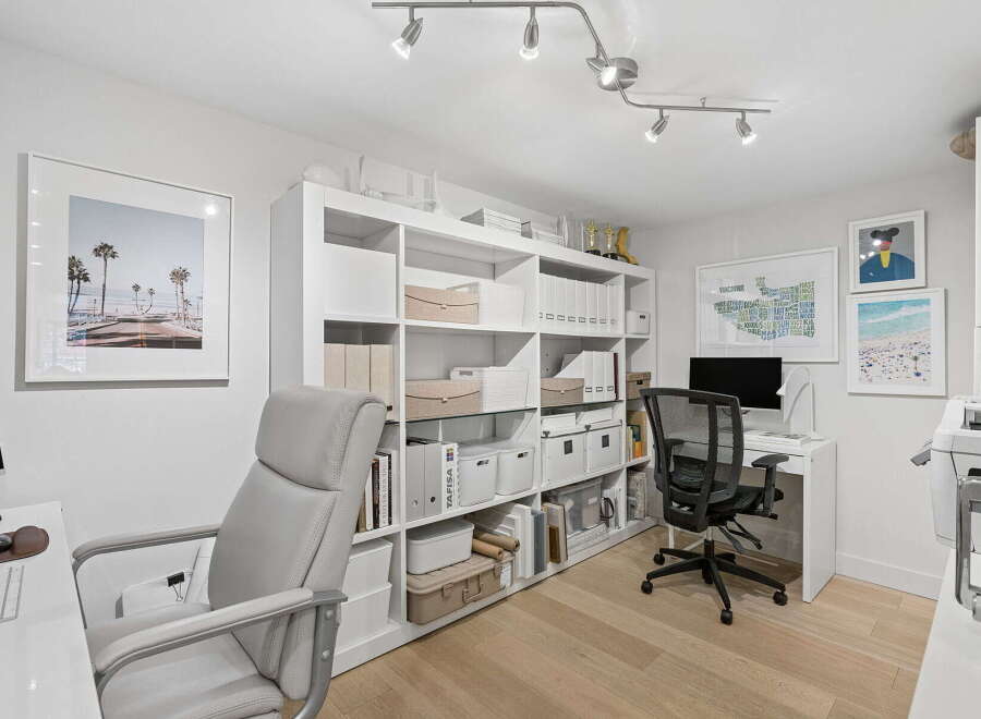 This modern home office features a spacious white shelving unit filled with storage bins and binders, perfect for organizing your workspace.