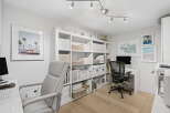 This modern home office features a spacious white shelving unit filled with storage bins and binders, perfect for organizing your workspace.