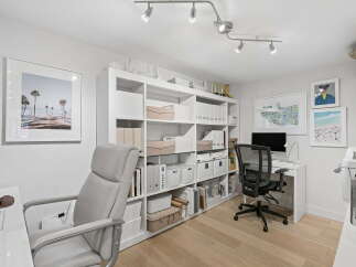 This modern home office features a spacious white shelving unit filled with storage bins and binders, perfect for organizing your workspace.