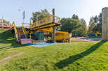 Discover this vibrant playground featuring a bright yellow slide and an elevated wooden walkway with safety railings.