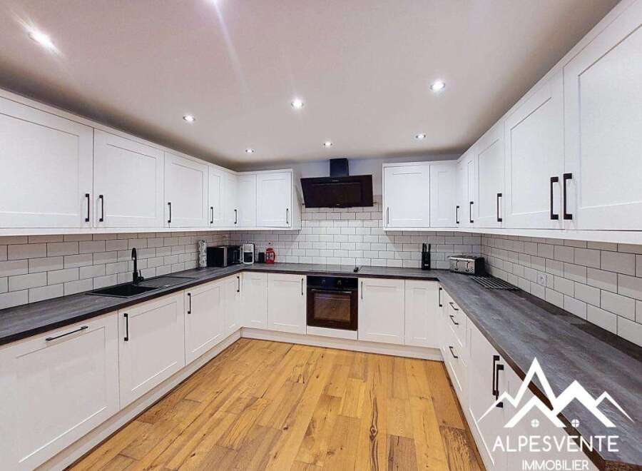 This modern kitchen boasts sleek white cabinetry with black hardware, complemented by a subway tile backsplash and dark countertops.