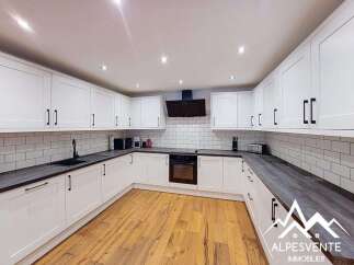 This modern kitchen boasts sleek white cabinetry with black hardware, complemented by a subway tile backsplash and dark countertops.