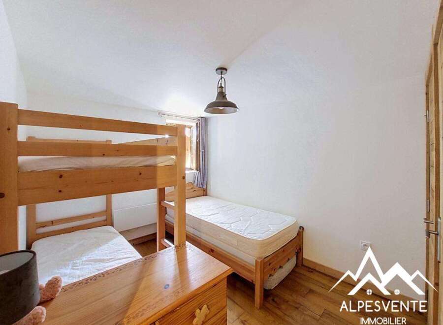 This charming bedroom features a wooden bunk bed, perfect for accommodating multiple guests, and a separate single bed for added flexibility.