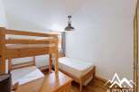 This charming bedroom features a wooden bunk bed, perfect for accommodating multiple guests, and a separate single bed for added flexibility.