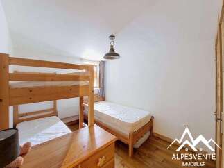This charming bedroom features a wooden bunk bed, perfect for accommodating multiple guests, and a separate single bed for added flexibility.