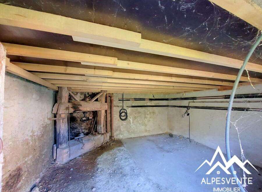 Discover the potential of this unfinished space, featuring exposed wooden beams and rustic stone walls, perfect for renovation.