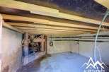 Discover the potential of this unfinished space, featuring exposed wooden beams and rustic stone walls, perfect for renovation.