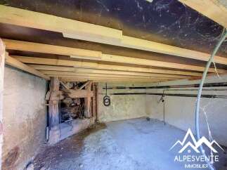 Discover the potential of this unfinished space, featuring exposed wooden beams and rustic stone walls, perfect for renovation.
