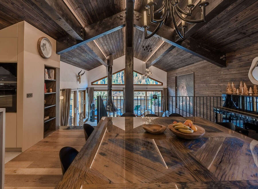 Experience rustic luxury in this stunning mountain retreat, featuring a grand wooden dining table perfect for gatherings.