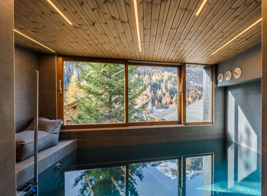 Experience luxury and relaxation in this stunning indoor pool area, featuring a serene ambiance and breathtaking mountain views.