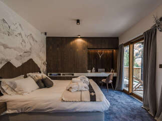 Experience alpine luxury in this beautifully appointed bedroom, featuring a striking mountain mural and rich wood paneling.