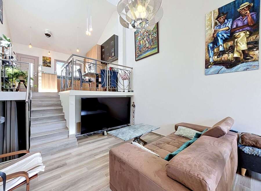 Experience modern living in this multi-level home featuring an open-concept living area with a large flat-screen TV and a stylish marble coffee table.