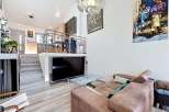 Experience modern living in this multi-level home featuring an open-concept living area with a large flat-screen TV and a stylish marble coffee table.