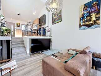 Experience modern living in this multi-level home featuring an open-concept living area with a large flat-screen TV and a stylish marble coffee table.