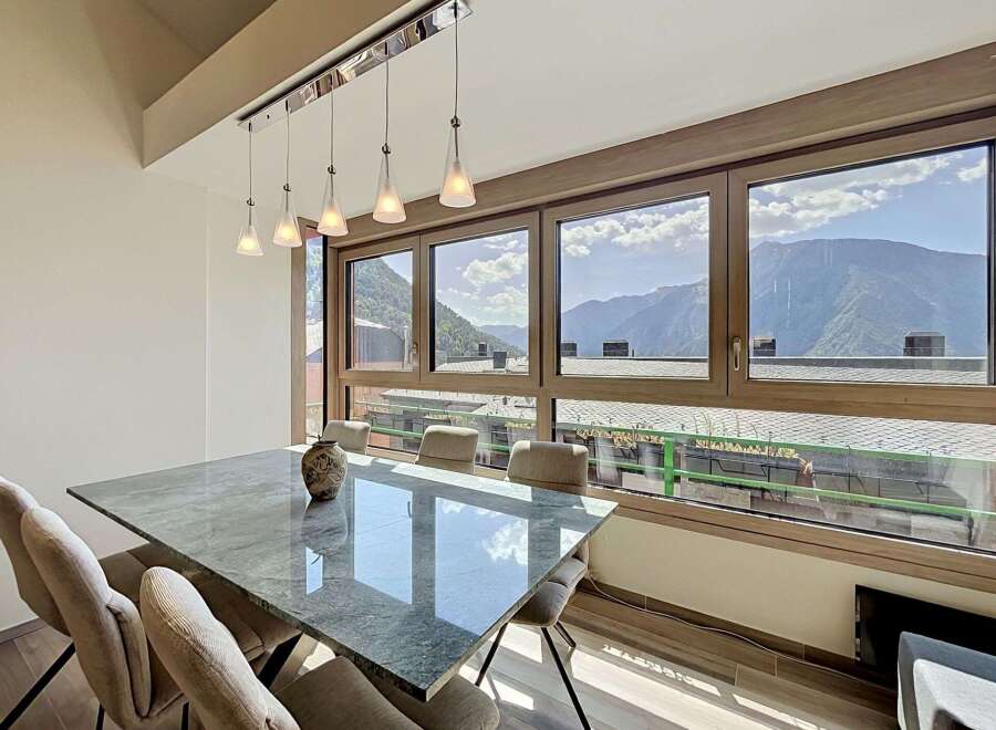 Experience breathtaking mountain views from this elegant dining room, featuring a sleek marble-top table and comfortable upholstered chairs.