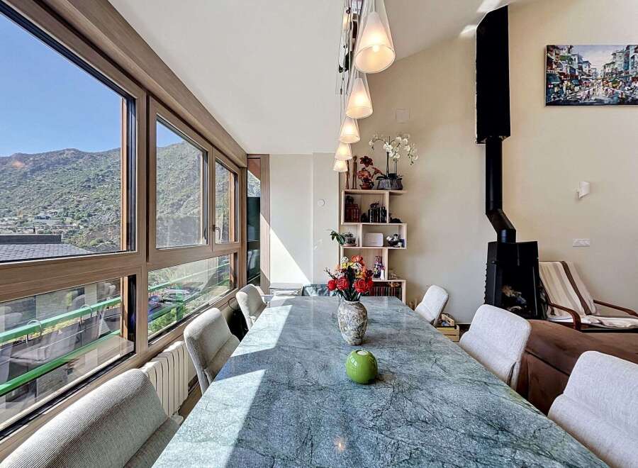 Experience breathtaking mountain views from this stunning dining room, featuring a large marble-top table perfect for gatherings.