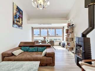 Experience modern living in this spacious apartment, featuring a comfortable brown sectional sofa adorned with teal and white accent pillows.