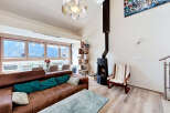 Experience breathtaking mountain views from this stunning living room, featuring a cozy brown leather sofa adorned with vibrant teal cushions.