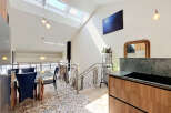 This modern dining area boasts a unique vaulted ceiling with skylights, flooding the space with natural light.