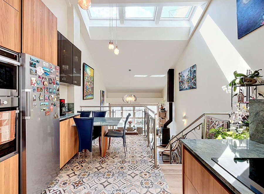 This modern kitchen boasts a sleek stainless steel refrigerator adorned with numerous magnets, complemented by warm wooden cabinetry and a built-in oven.