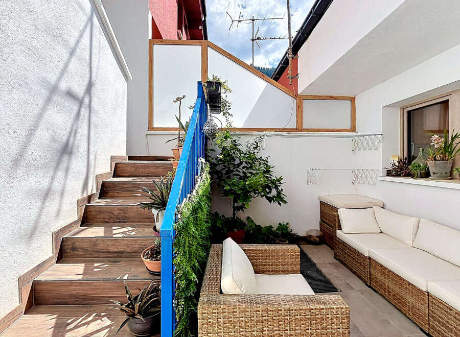 Enjoy outdoor living with this charming patio featuring comfortable wicker seating and a stylish outdoor sofa.