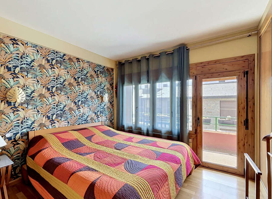 Step into this inviting bedroom featuring a striking tropical-themed wallpaper that adds a vibrant touch to the space.