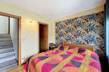 Step into this inviting bedroom featuring a striking tropical-themed wallpaper that adds a vibrant touch to the space.