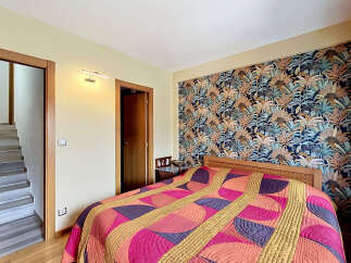 Step into this inviting bedroom featuring a striking tropical-themed wallpaper that adds a vibrant touch to the space.