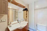 This modern bathroom features a sleek vanity with a white basin and chrome faucet, complemented by warm wood cabinetry.