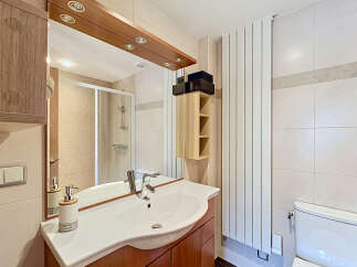 This modern bathroom features a sleek vanity with a white basin and chrome faucet, complemented by warm wood cabinetry.