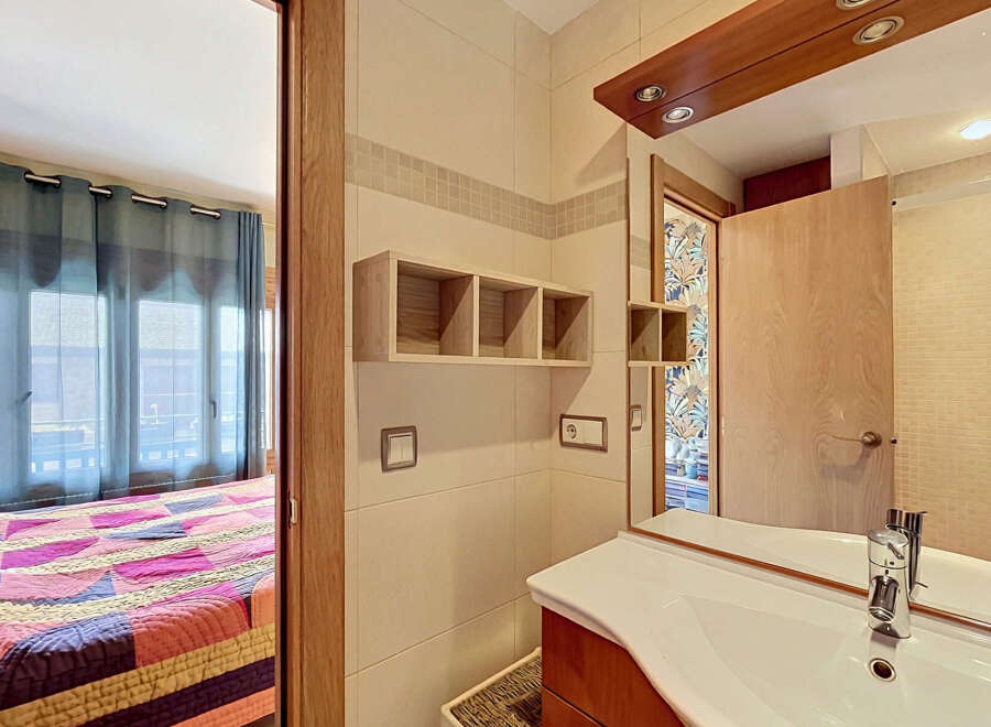 This charming property features a well-appointed bathroom with a modern sink and vanity, complemented by elegant tiled walls and wooden accents.