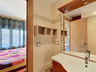 This charming property features a well-appointed bathroom with a modern sink and vanity, complemented by elegant tiled walls and wooden accents.