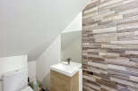 Discover this modern bathroom featuring a sleek white toilet and a stylish vanity with a wooden cabinet.