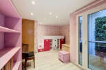 This charming children's room features a playful butterfly-themed wallpaper and a loft bed with integrated storage in vibrant pink and white.