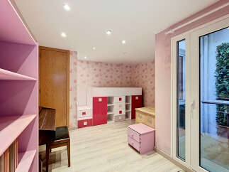 This charming children's room features a playful butterfly-themed wallpaper and a loft bed with integrated storage in vibrant pink and white.