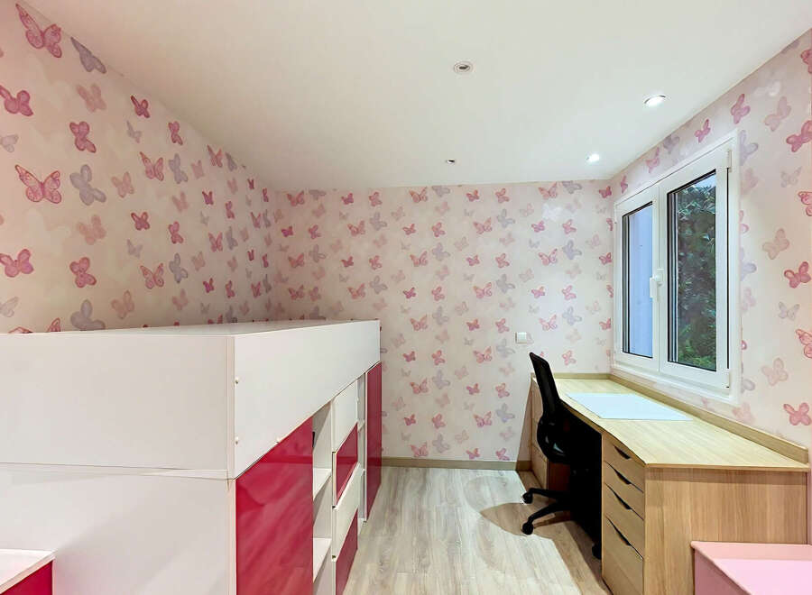 This charming bedroom features a playful butterfly-themed wallpaper, creating a whimsical atmosphere perfect for a child or teen.