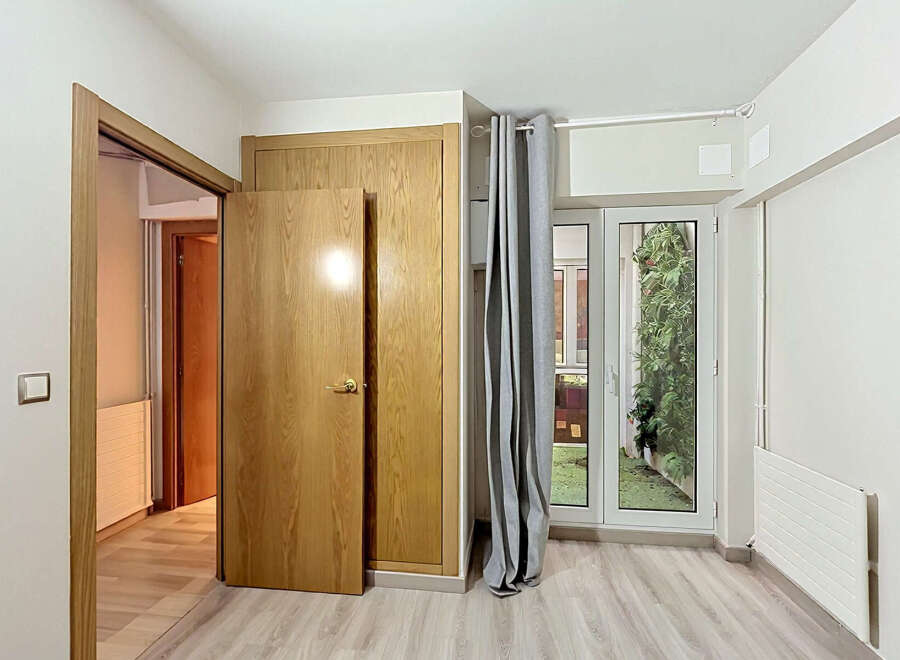 Discover this charming room featuring a light wood door and a built-in closet, offering ample storage solutions.