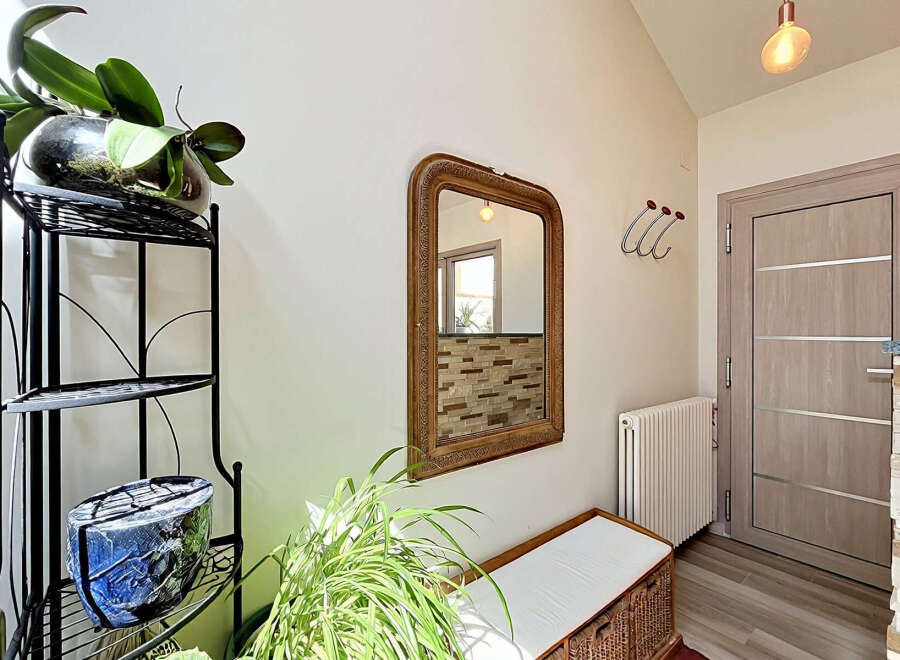 Welcome guests into a bright and airy entryway featuring a decorative mirror and a comfortable bench.