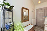 Welcome guests into a bright and airy entryway featuring a decorative mirror and a comfortable bench.