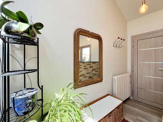 Welcome guests into a bright and airy entryway featuring a decorative mirror and a comfortable bench.