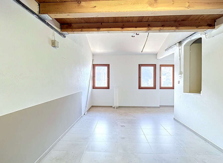 Discover this bright and airy space featuring a rustic wooden beam ceiling and large windows that flood the room with natural light.