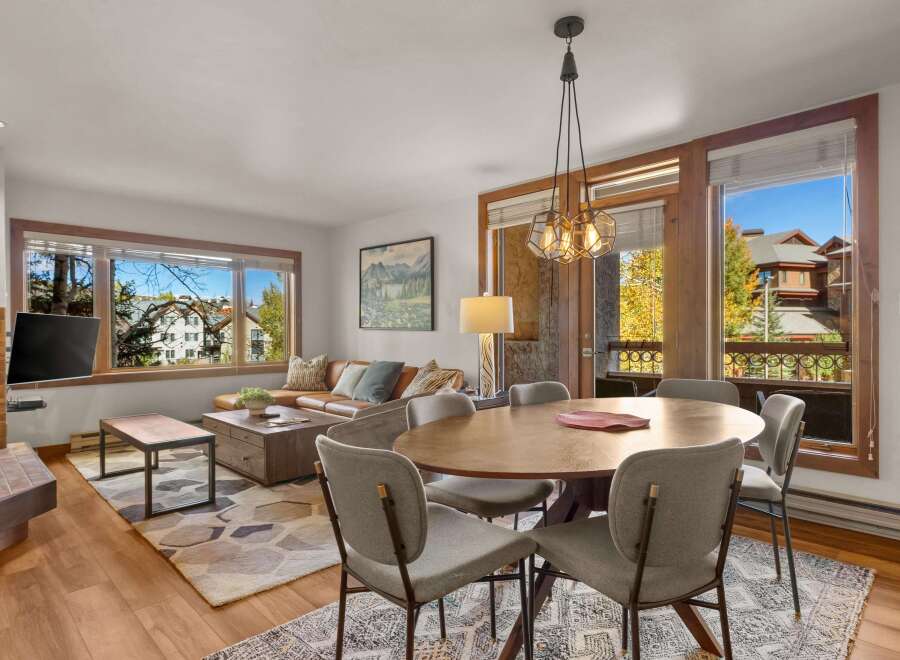 Experience comfortable living in this inviting dining and living area, featuring a spacious leather sectional sofa and a large wooden coffee table perfect for gatherings.