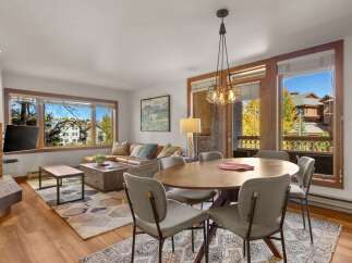 Experience comfortable living in this inviting dining and living area, featuring a spacious leather sectional sofa and a large wooden coffee table perfect for gatherings.