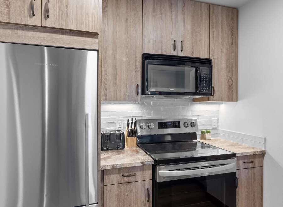Experience modern living in this beautifully appointed kitchen, featuring sleek stainless steel appliances including a Fisher & Paykel refrigerator and a GE microwave.