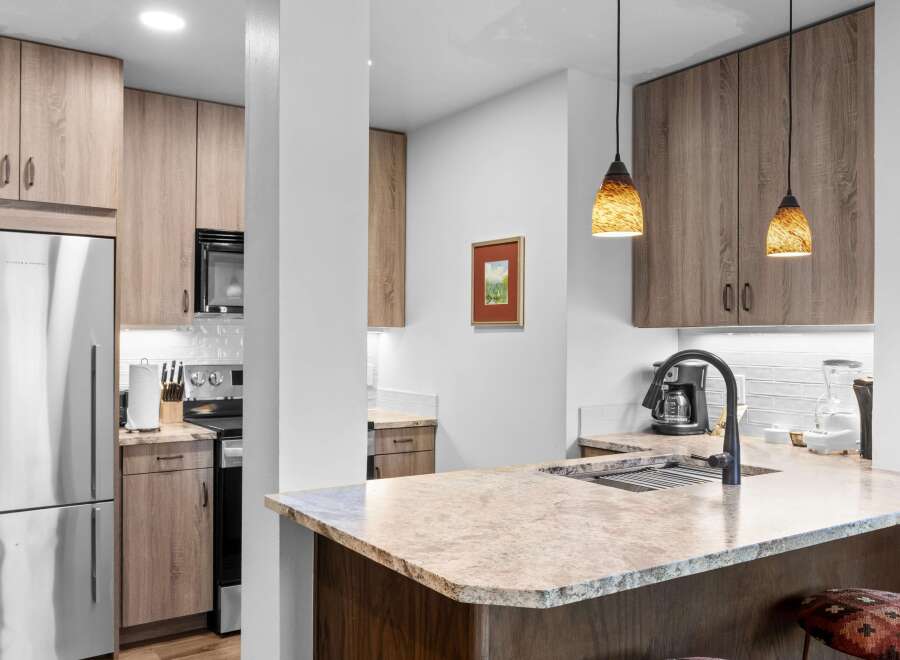 Step into this modern kitchen featuring sleek, light wood cabinetry and granite countertops.