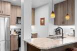Step into this modern kitchen featuring sleek, light wood cabinetry and granite countertops.