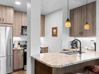 Step into this modern kitchen featuring sleek, light wood cabinetry and granite countertops.